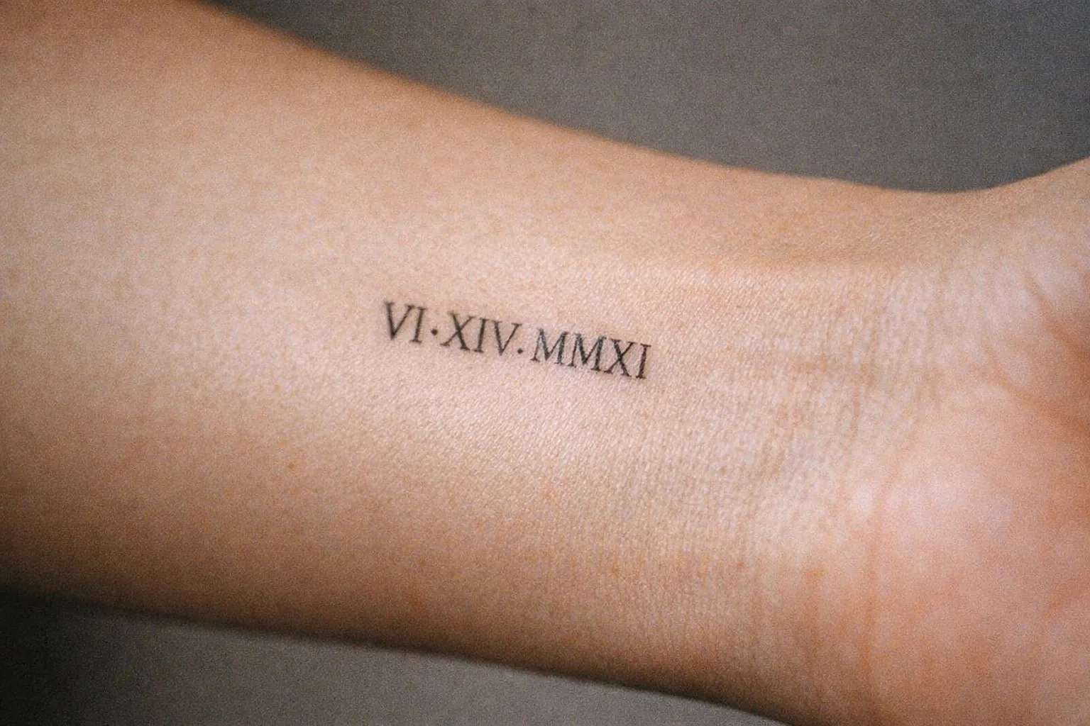 Tiny Roman numeral tattoo near the wrist on inner forearm