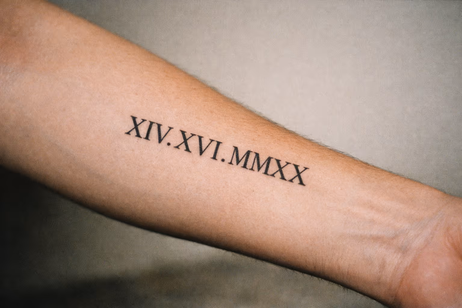 Editorial close-up of a bold Roman numeral tattoo on a forearm