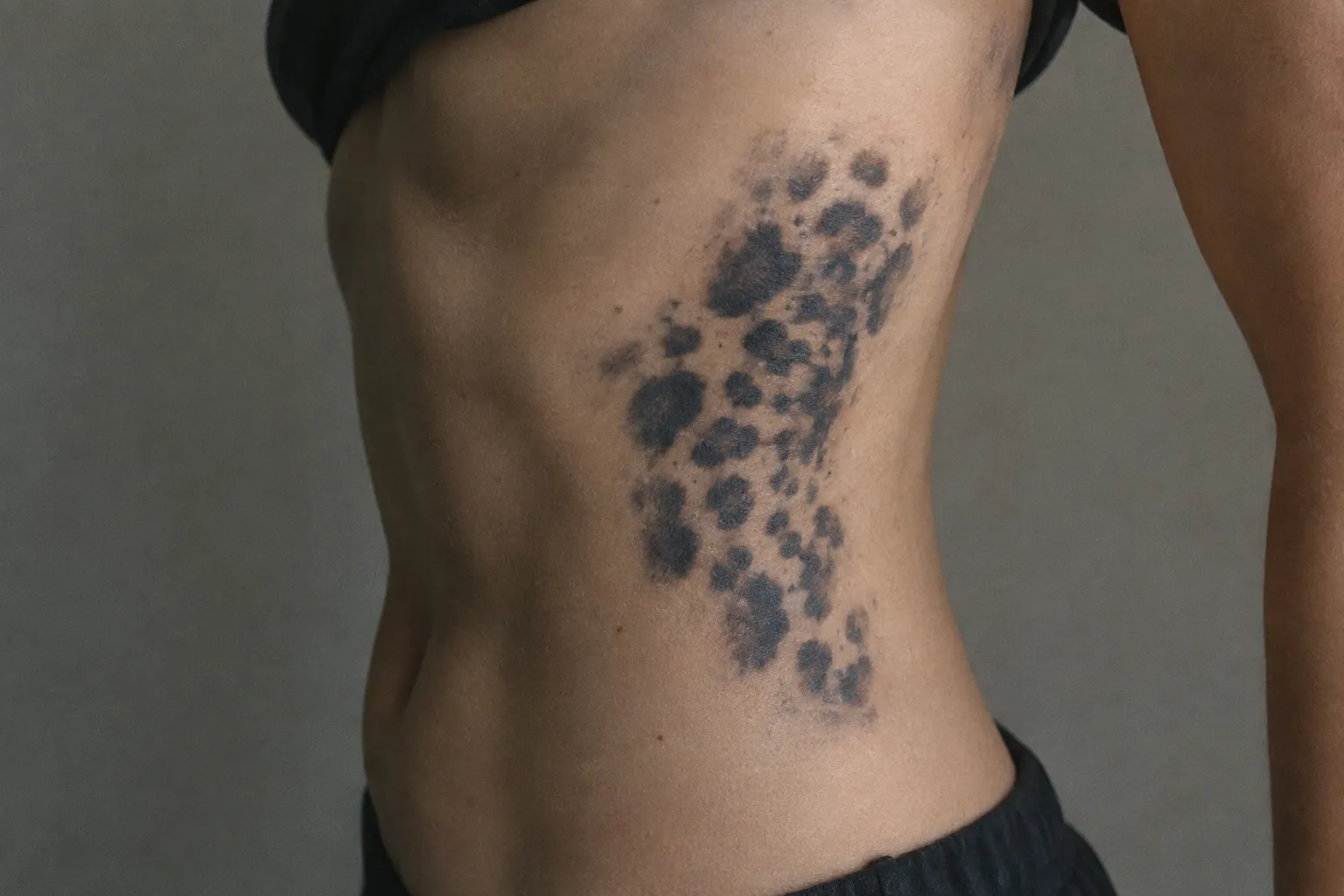 A person's side shows a dark animal-print tattoo across the ribs.