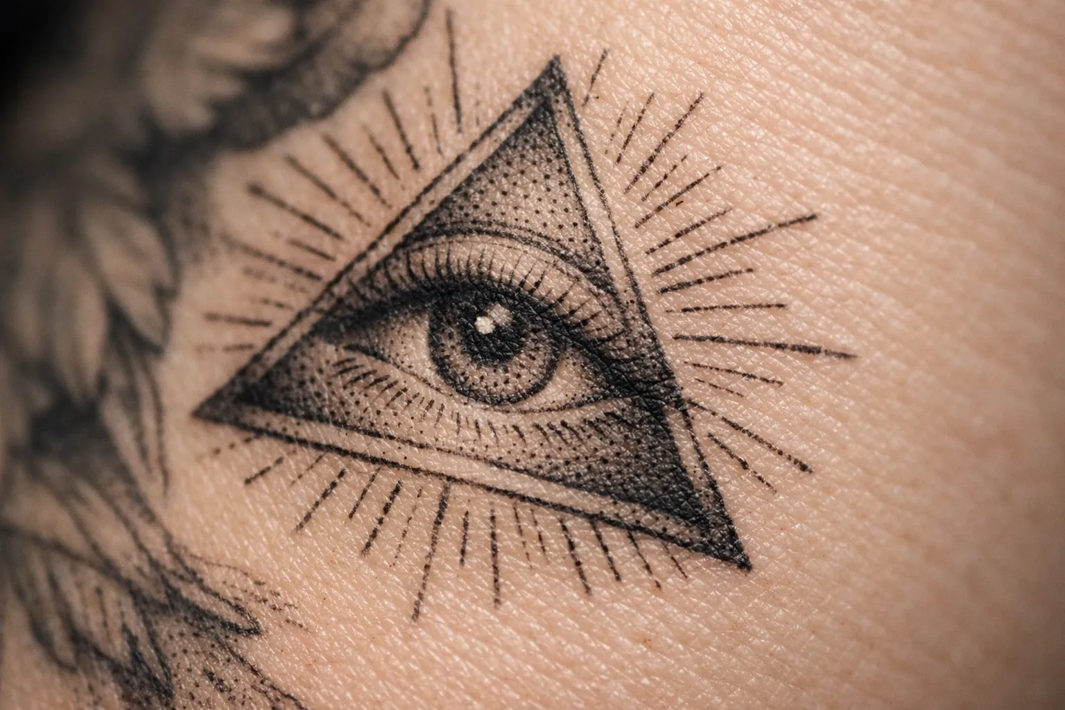 A close-up of a realistic all-seeing eye tattoo within a triangle on human skin.