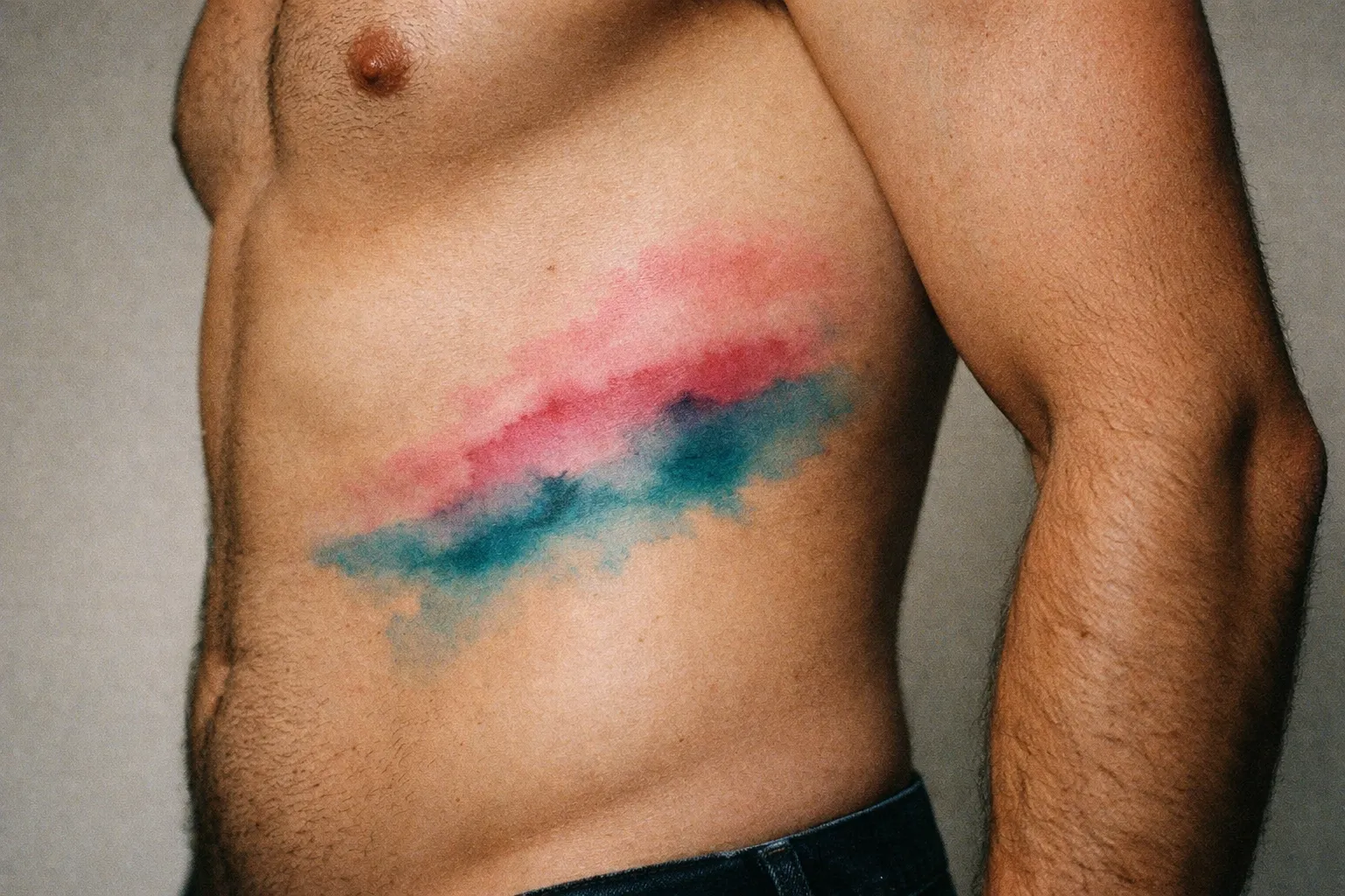 A person with a colorful watercolor-style tattoo on their ribcage.