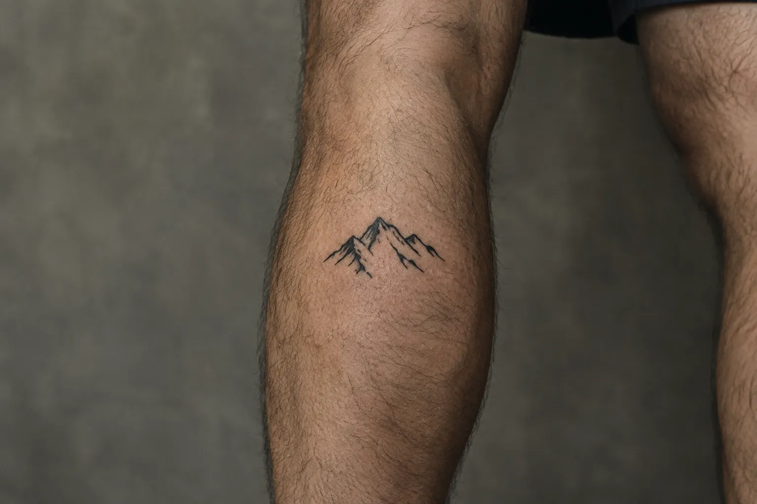 A small mountain tattoo on a man's lower leg.