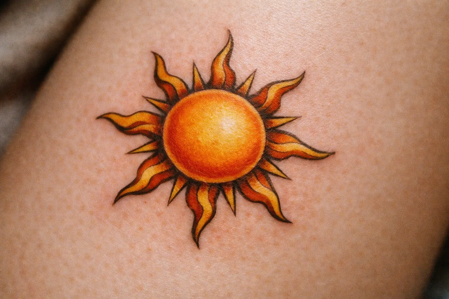 A vibrant sun tattoo is inked on a person's skin.