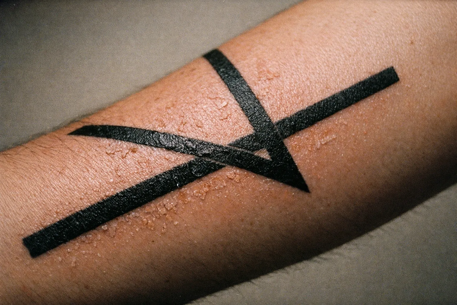 Close-up of a forearm tattoo in late-stage healing, showing crisp linework and natural skin texture under soft studio lighting