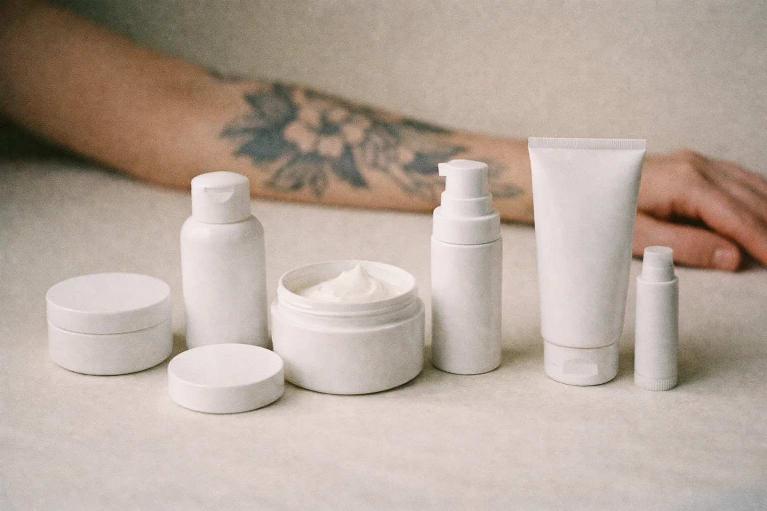 Unlabeled aftercare containers with forearm tattoo in the background