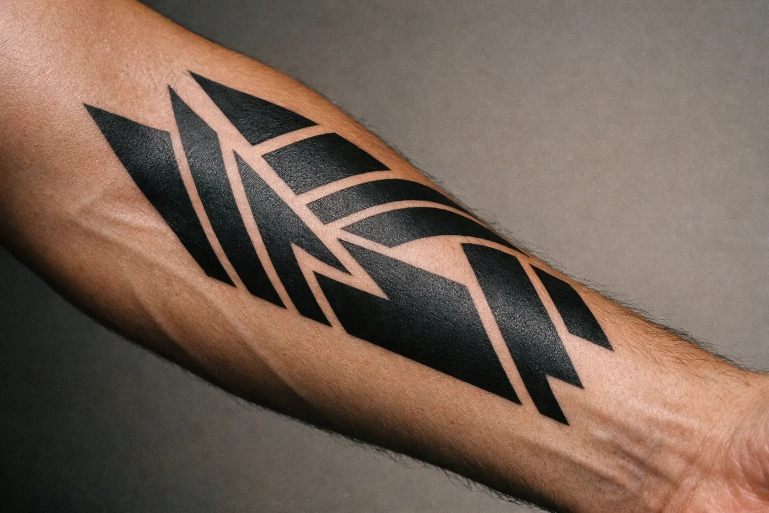 Macro close-up of inner forearm with bold geometric blackwork tattoo