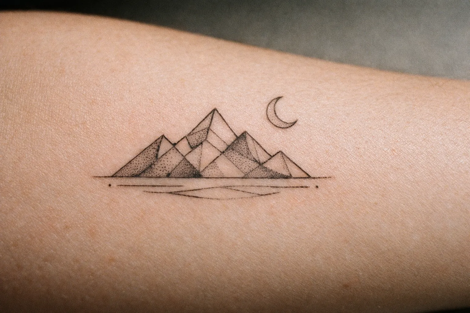 Thin-line tattoo on forearm with subtle shading; skin texture and natural tones visible