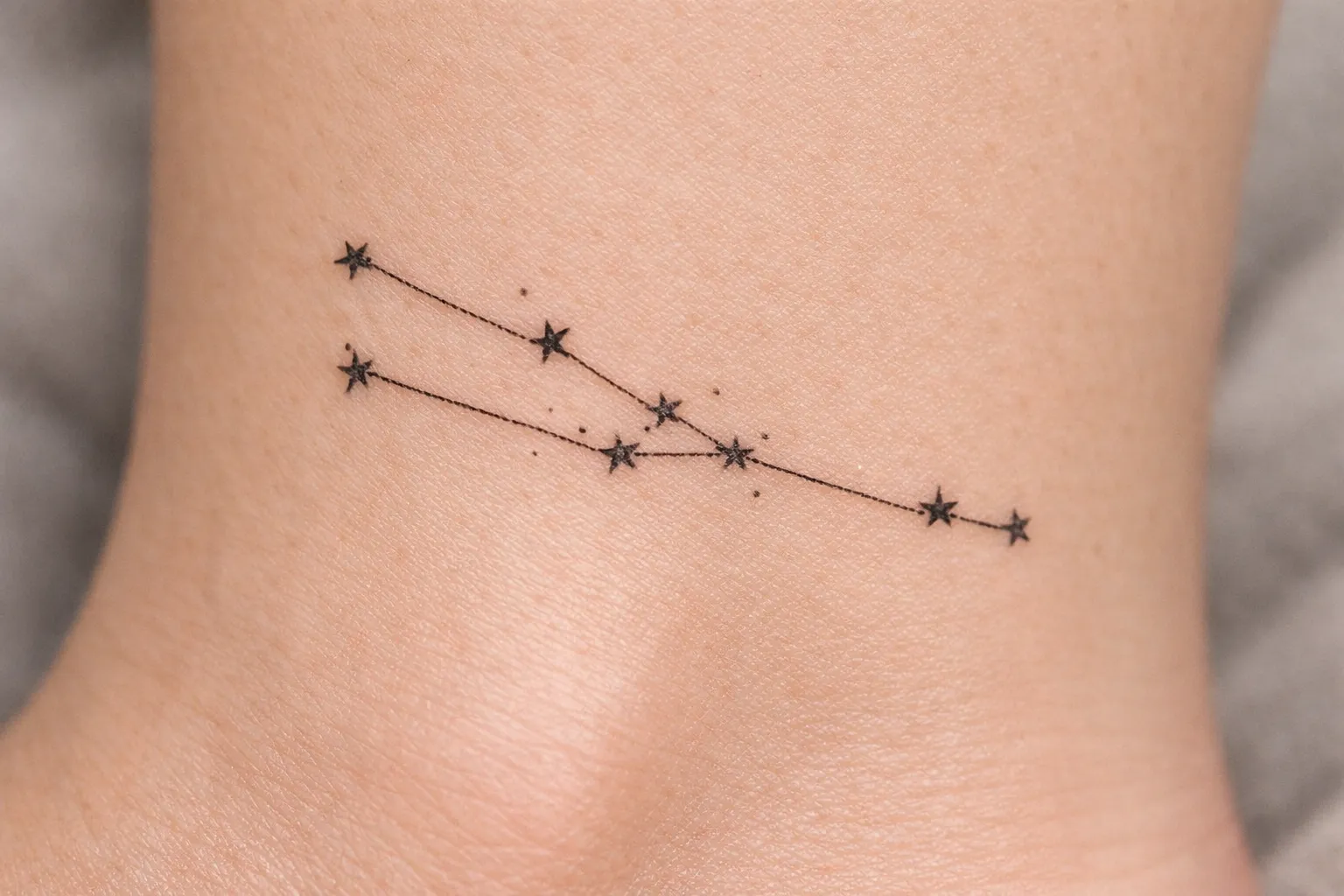 A Taurus constellation tattoo is inked on the side of an ankle.