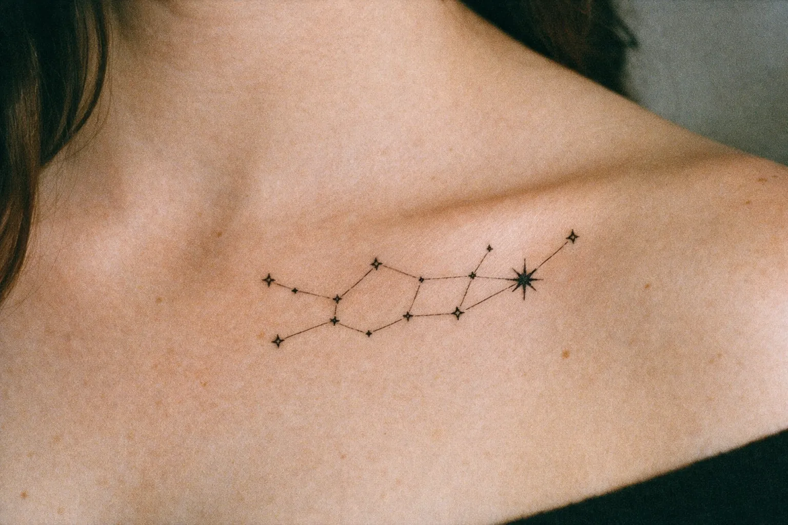 A person with a Virgo constellation tattoo on their upper chest near the collarbone.
