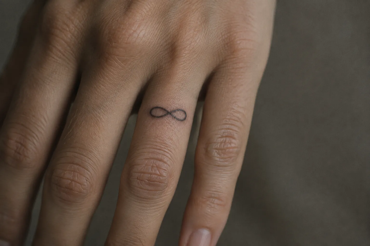 A hand with a small infinity tattoo on a finger.